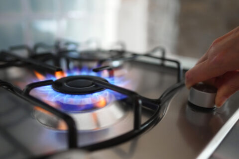 Woman turning on the gas burner on the stove.